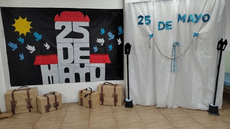 Escenografía del 25 de Mayo en el jardín: Cabildo de cartulina, palomas, faroles y valijas de cartón